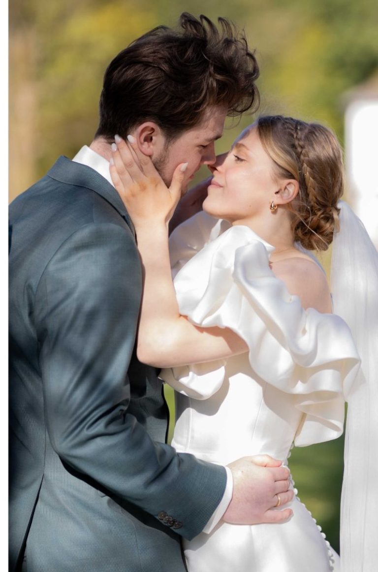 Hochzeitspaar umarmt sich liebevoll am Ufer.