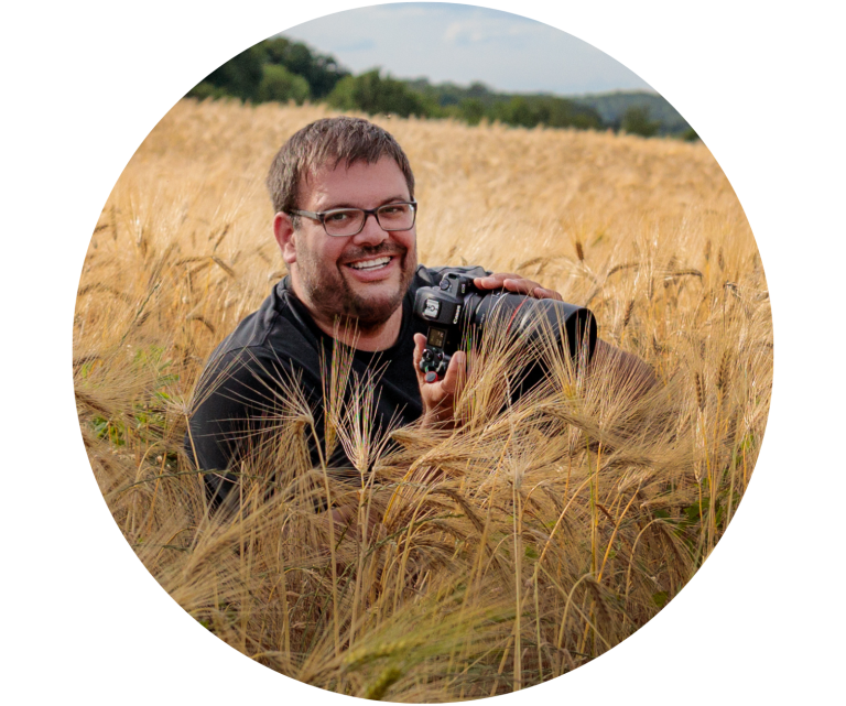 Lächelnder Fotograf mit Kamera in einem goldenen Baumwollfeld in Bad Driburg