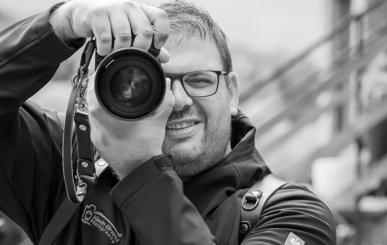 Hochzeitsfotograf Warburg Hochzeitsfotograf aus Warburg hält eine Kamera und lächelt.
