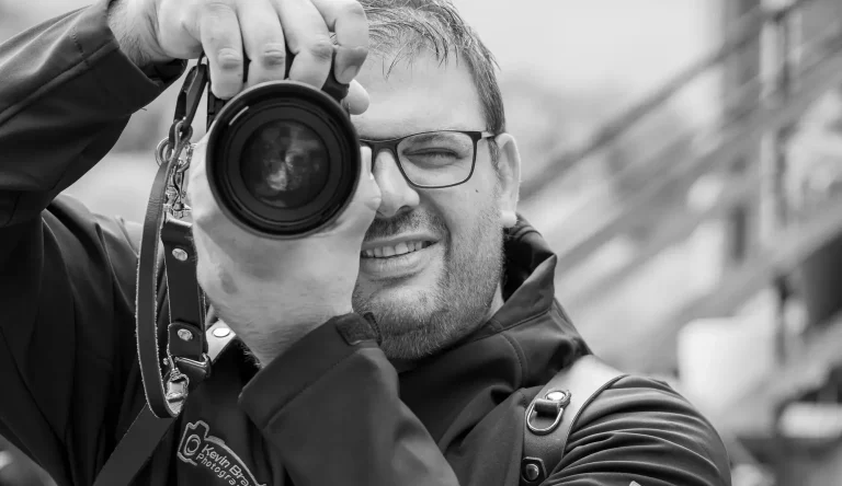 Hochzeitsfotograf Höxter Ein lächelnder Fotograf aus Bad Driburg hält eine Kamera und schaut durch den Sucher.