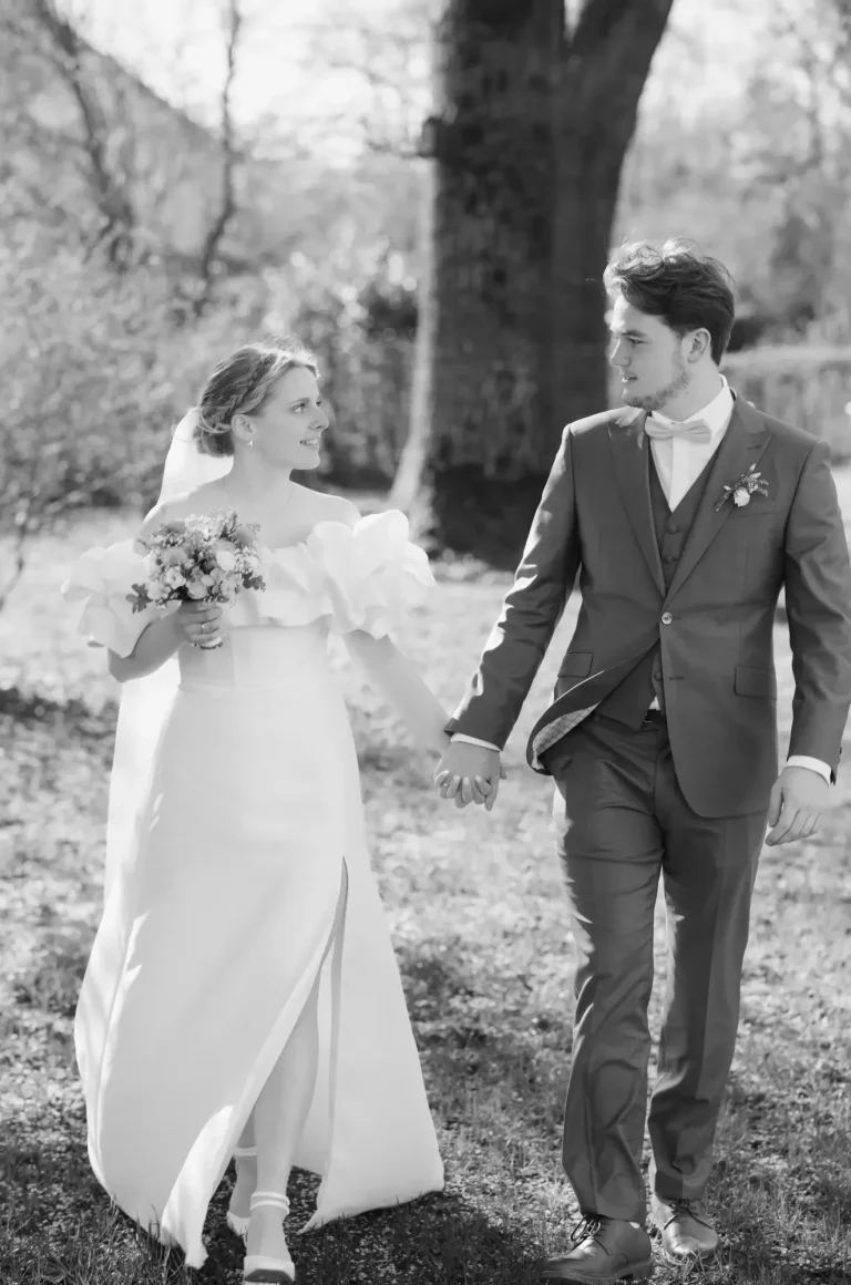 Hochzeitspärchen in Bad Driburg Paar in Hochzeitskleidung, Hand in Hand in einer sonnigen, natürlichen Umgebung.