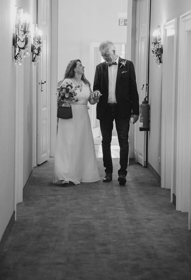 Hochzeit Driburg Ein Brautpaar geht gemeinsam durch einen hellen Flur.