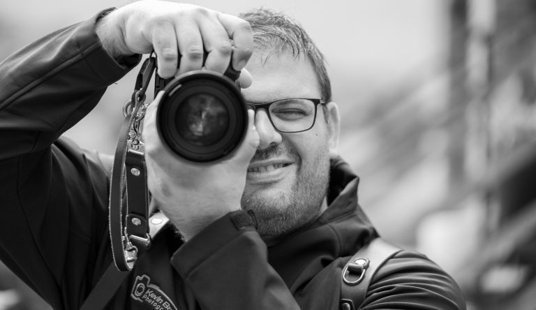 Hochzeitsfotograf Höxter Ein lächelnder Fotograf aus Bad Driburg hält eine Kamera und schaut durch den Sucher.
