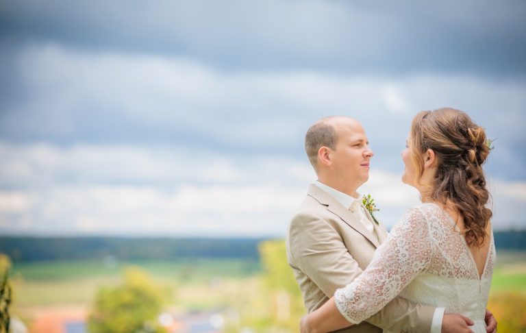 Hochzeit in Höxter Brautpaar aus Höxter umarmt sich vor bewölktem Himmel, romantische Stimmung im Freien.