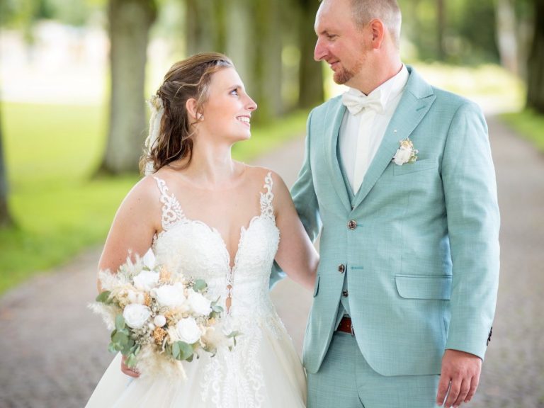Hochzeit in Bad Driburg-Bad Hermansborn Braut und Bräutigam lächeln sich auf einem gepflasterten Weg in Bad Hermansborn-Bad Driburg an.