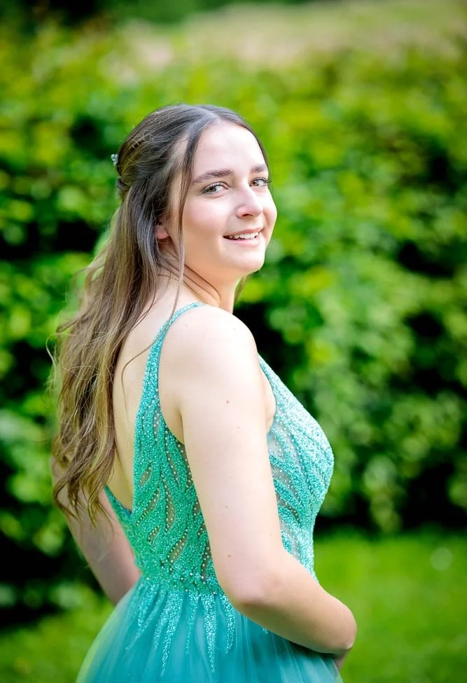 Hochzeit Bad Driburg Junge Frau mit langen Haaren in einem grünen Kleid, lächelnd im Freien.