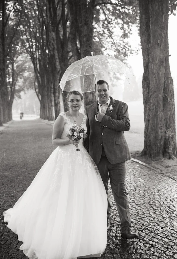 Hochzeitsfotos höxter Brautpaar mit transparentem Regenschirm, umgeben von Bäumen in nebliger Atmosphäre.